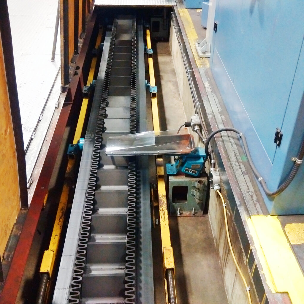 Underfloor conveyor in trench takes products from presses to packaging